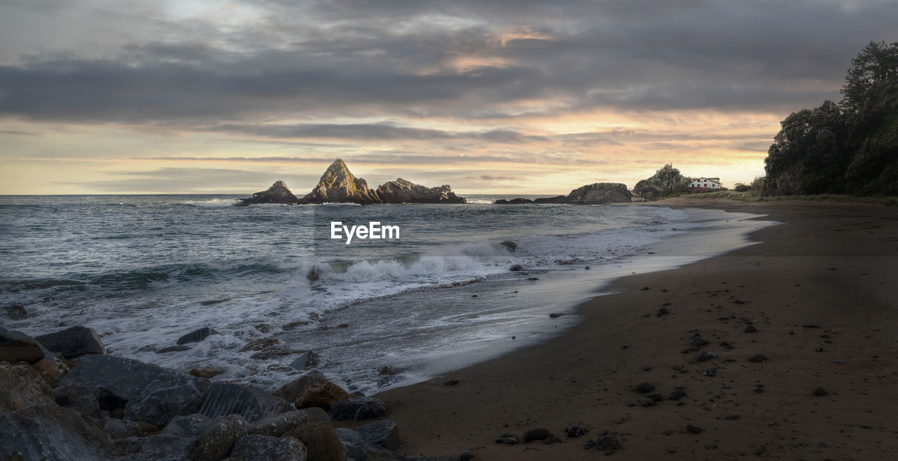 scenic view of beach against cloudy sky