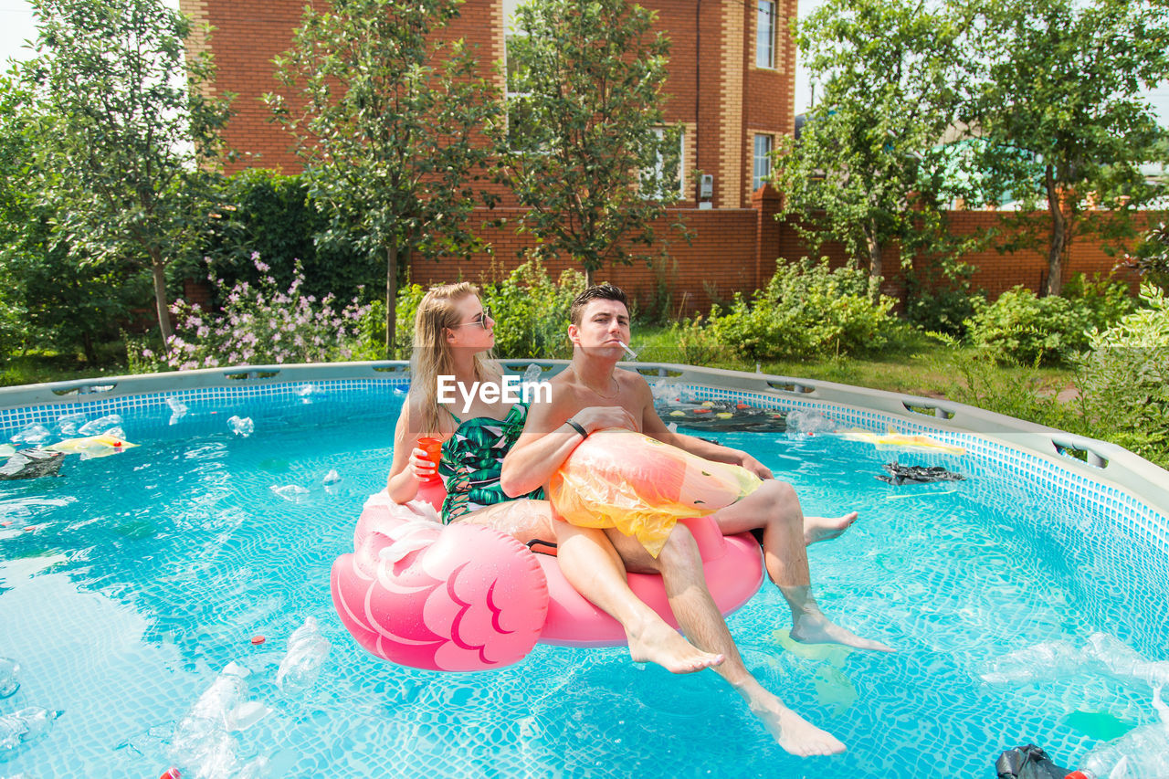 WOMAN SITTING IN SWIMMING POOL AT PARK