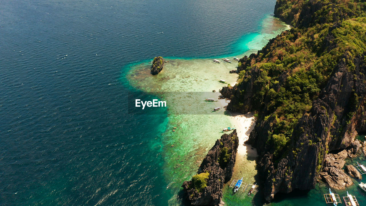 Aerial drone tropical landscape bay with beach and clear blue water surrounded by cliffs. el nido