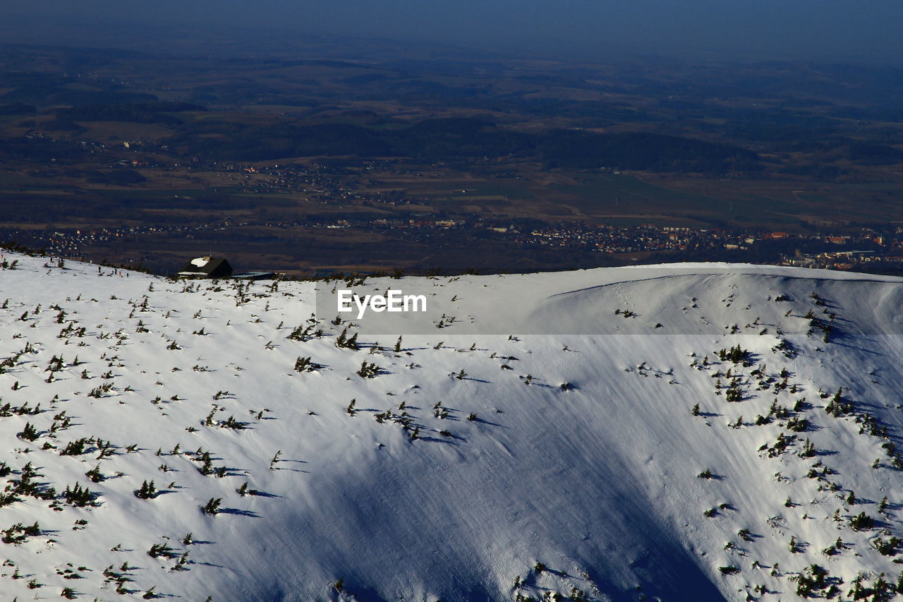 Aerial view of snow covered land against sky