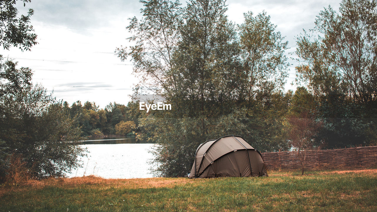 Tent on field by lake against sky