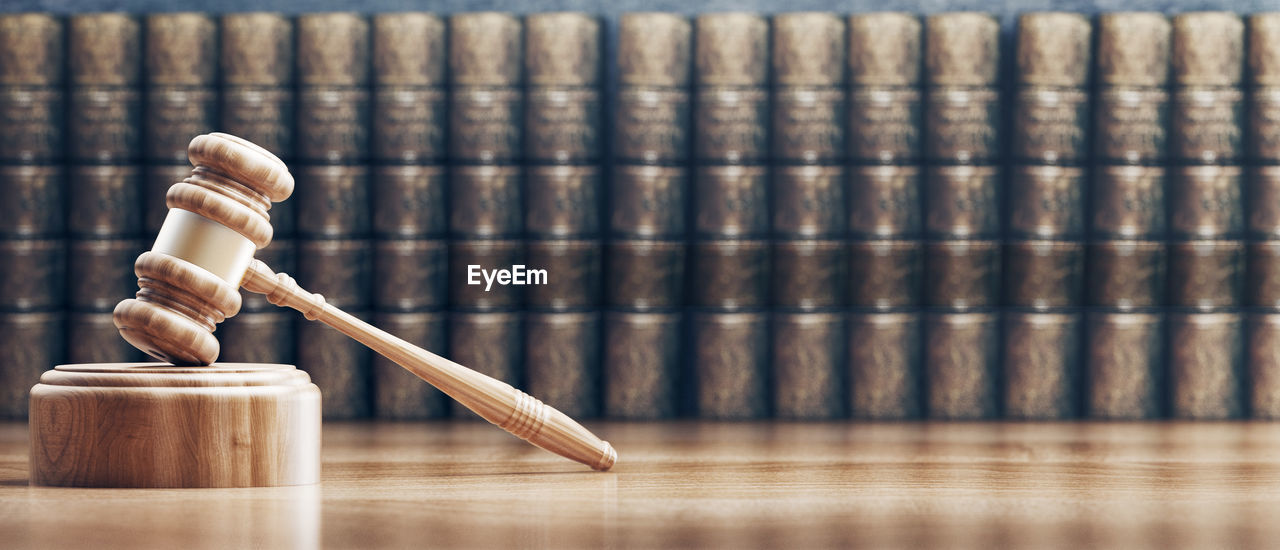 Close-up of wooden gavel against books on table