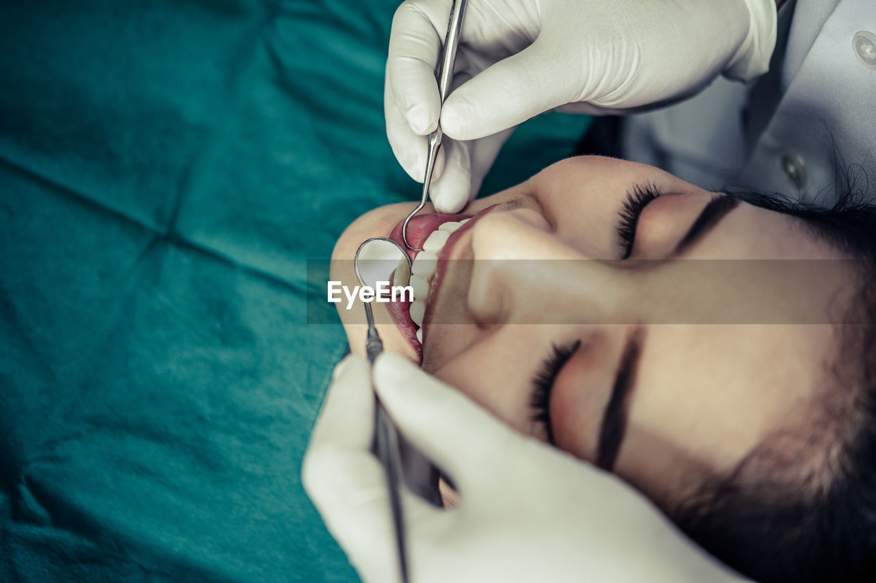 Close-up of young woman getting her teeth examined by dentist