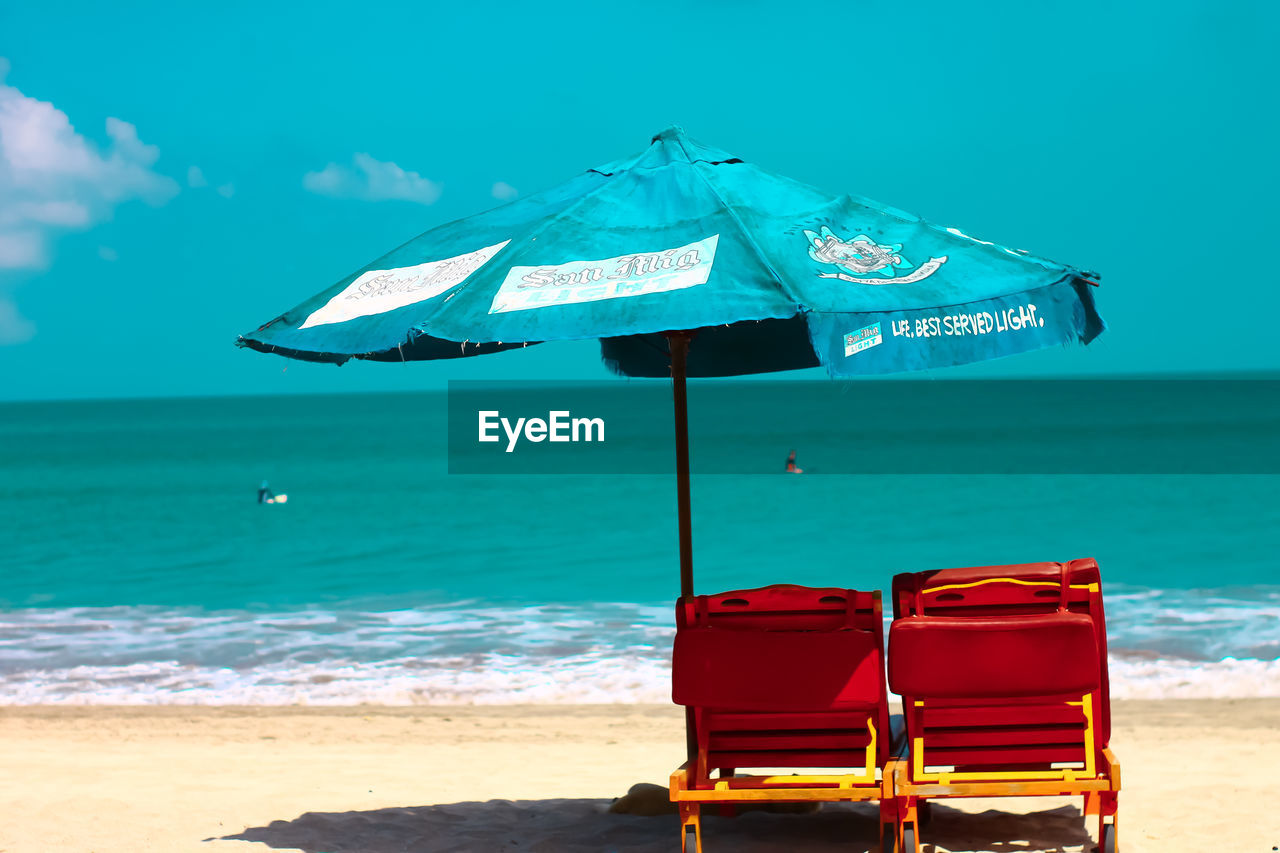 DECK CHAIRS ON BEACH AGAINST SKY