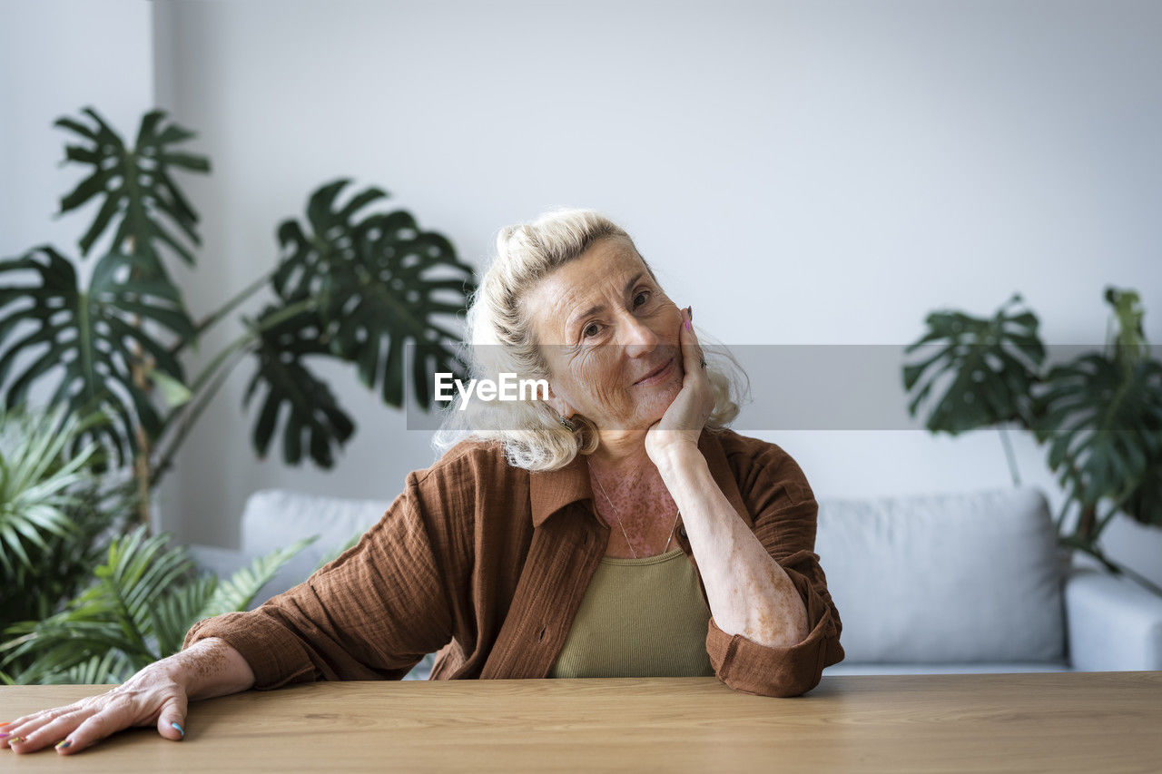 Smiling elderly woman leaning on elbow at home