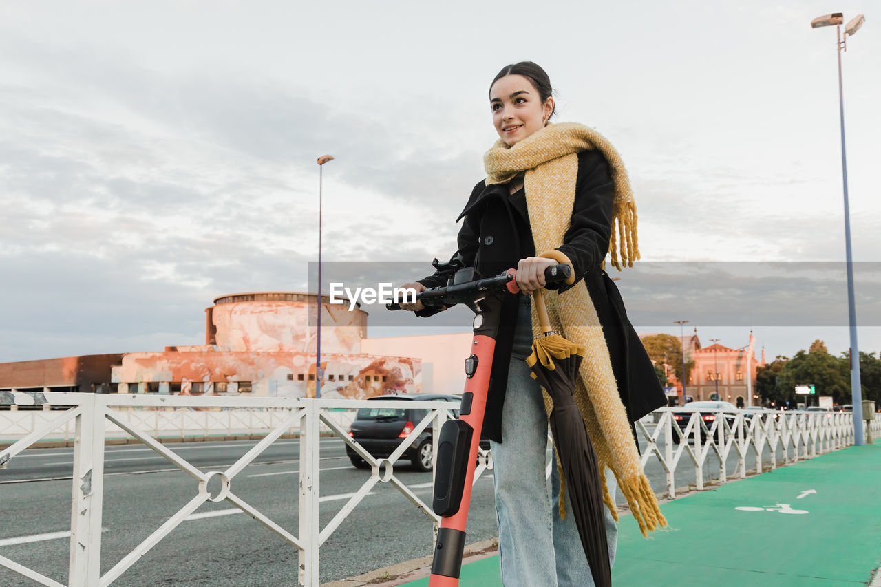 Teenager riding electric push scooter in front of sky