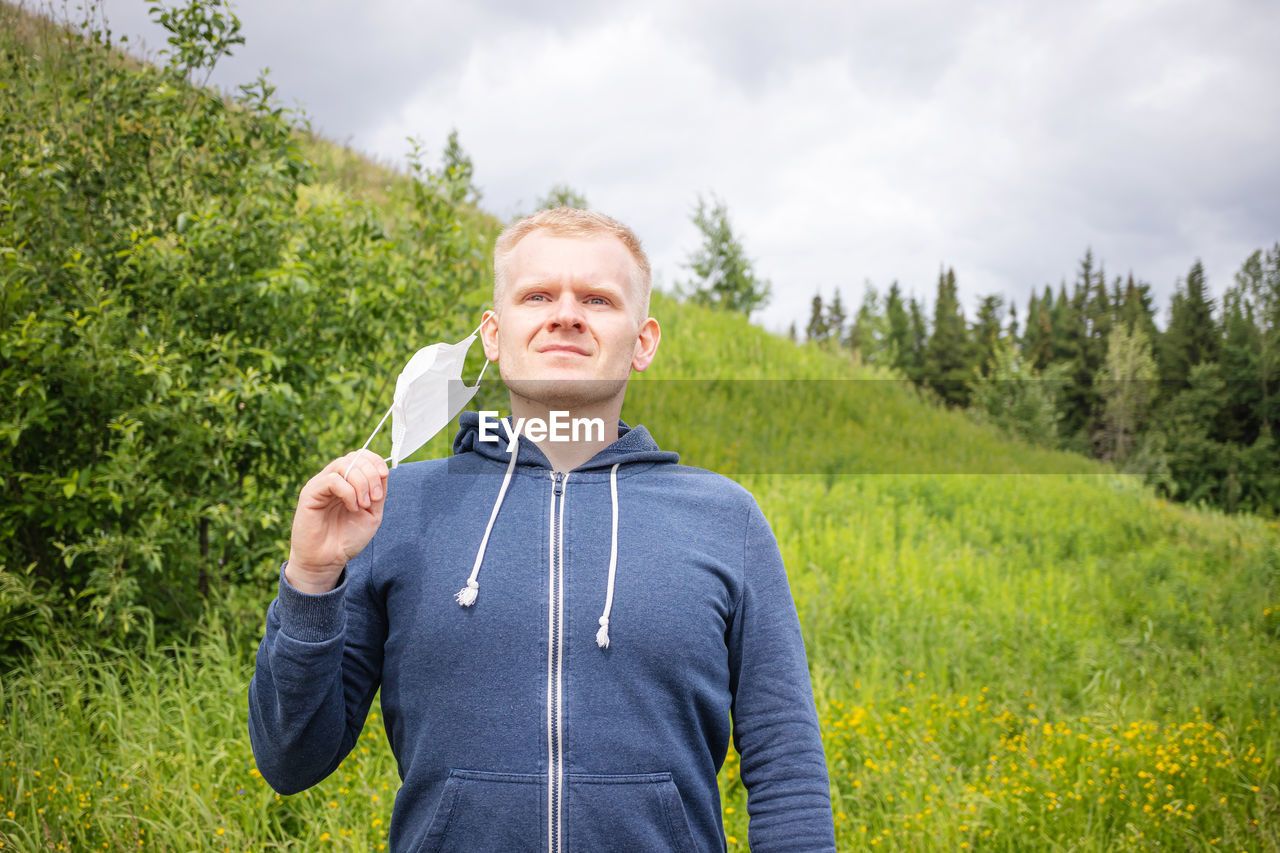 Concept of quarantine ending, walks alone. european young male removes a disposable medical mask. 