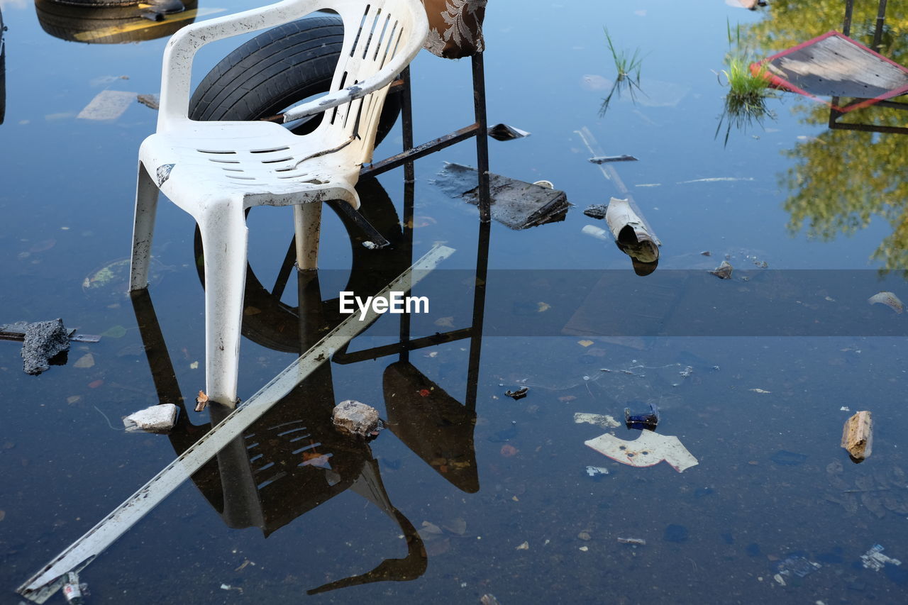 High angle view of broken chairs and tires in water on field