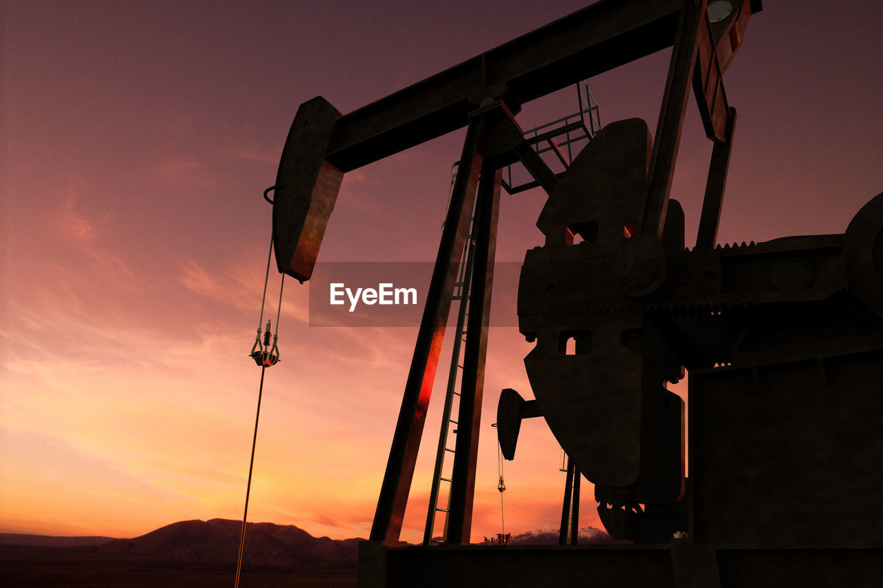 Low angle silhouette oil pump against clear sky during sunset