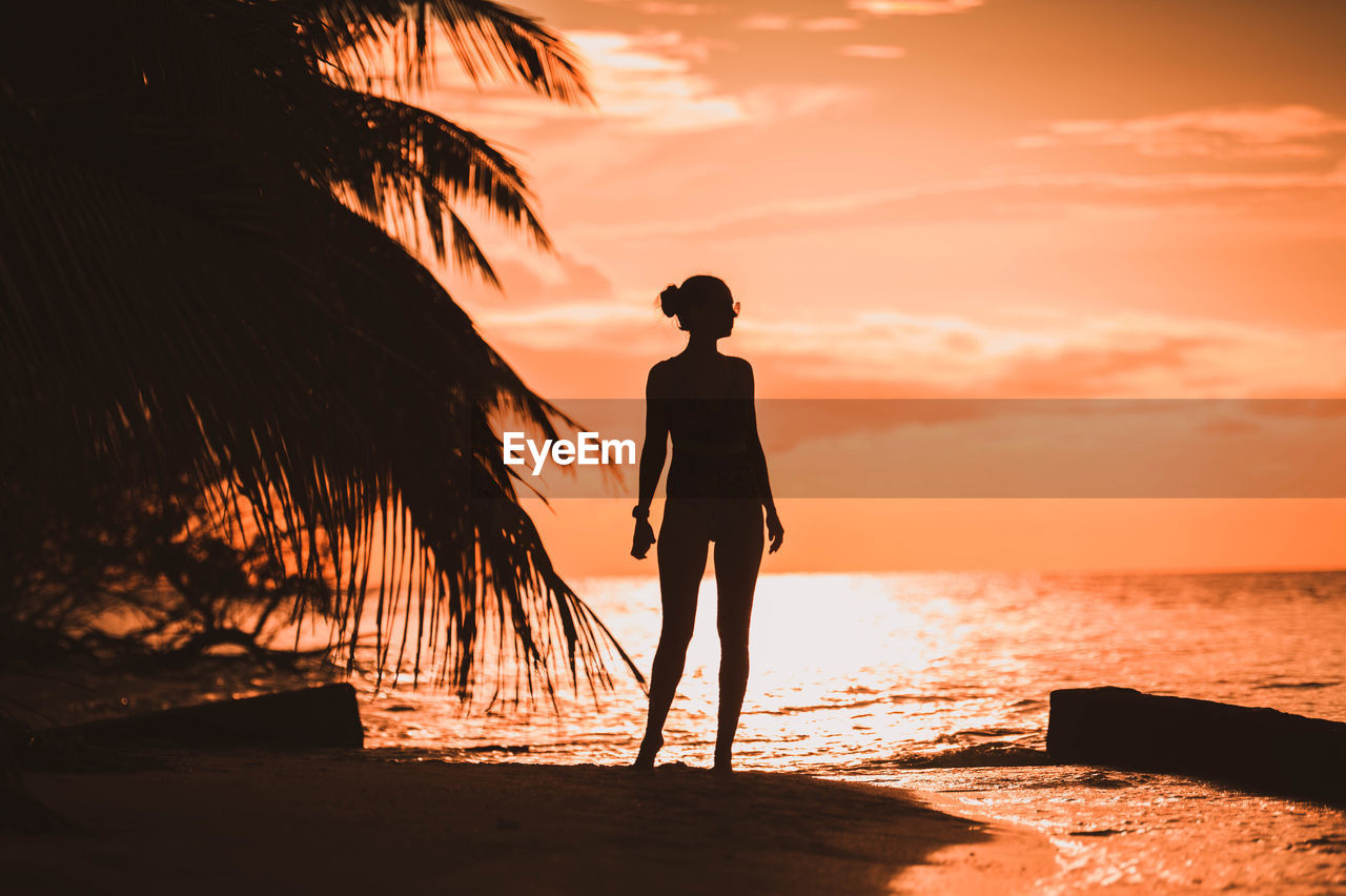 silhouette woman standing on beach against sky during sunset