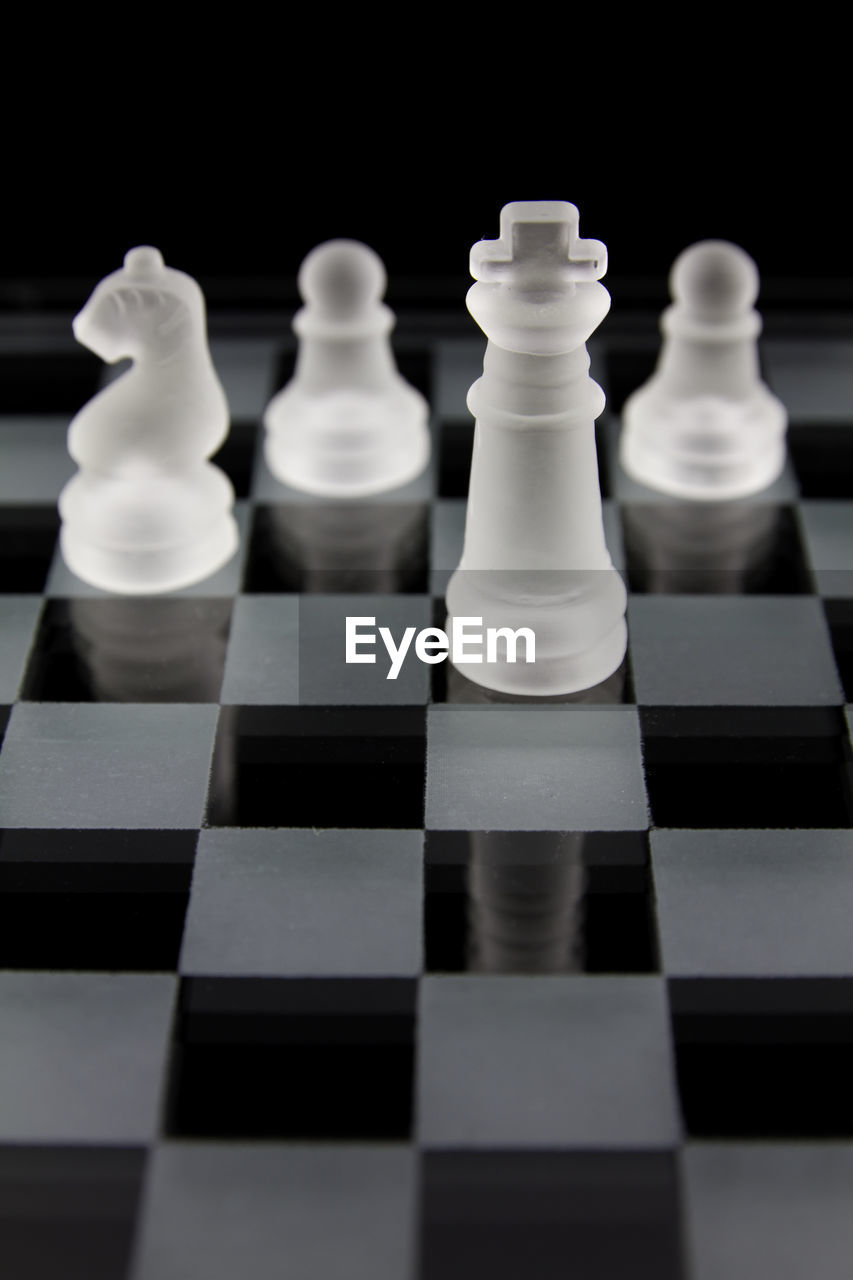 Close-up of glass pieces on chess board against black background