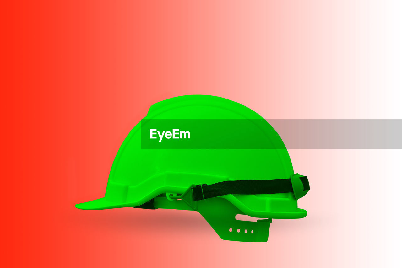 Close-up of green hardhat on red background