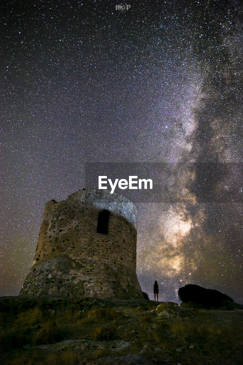 Man standing on tower against sky at night
