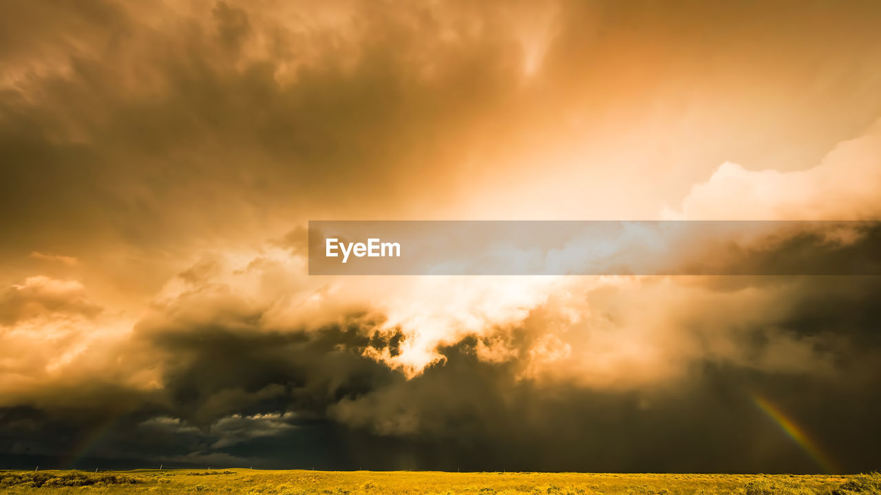 sky, cloud, environment, beauty in nature, landscape, storm, nature, dramatic sky, land, sunlight, plant, scenics - nature, field, thunderstorm, rural scene, yellow, storm cloud, cloudscape, morning, sunbeam, no people, horizon, grass, plain, agriculture, tranquility, outdoors, summer, sun, atmospheric mood, vibrant color, multi colored, awe, horizon over land, tranquil scene, idyllic, moody sky, tree, overcast, meadow, wet, crop, rain, light - natural phenomenon, gold, back lit, non-urban scene, dusk, dark