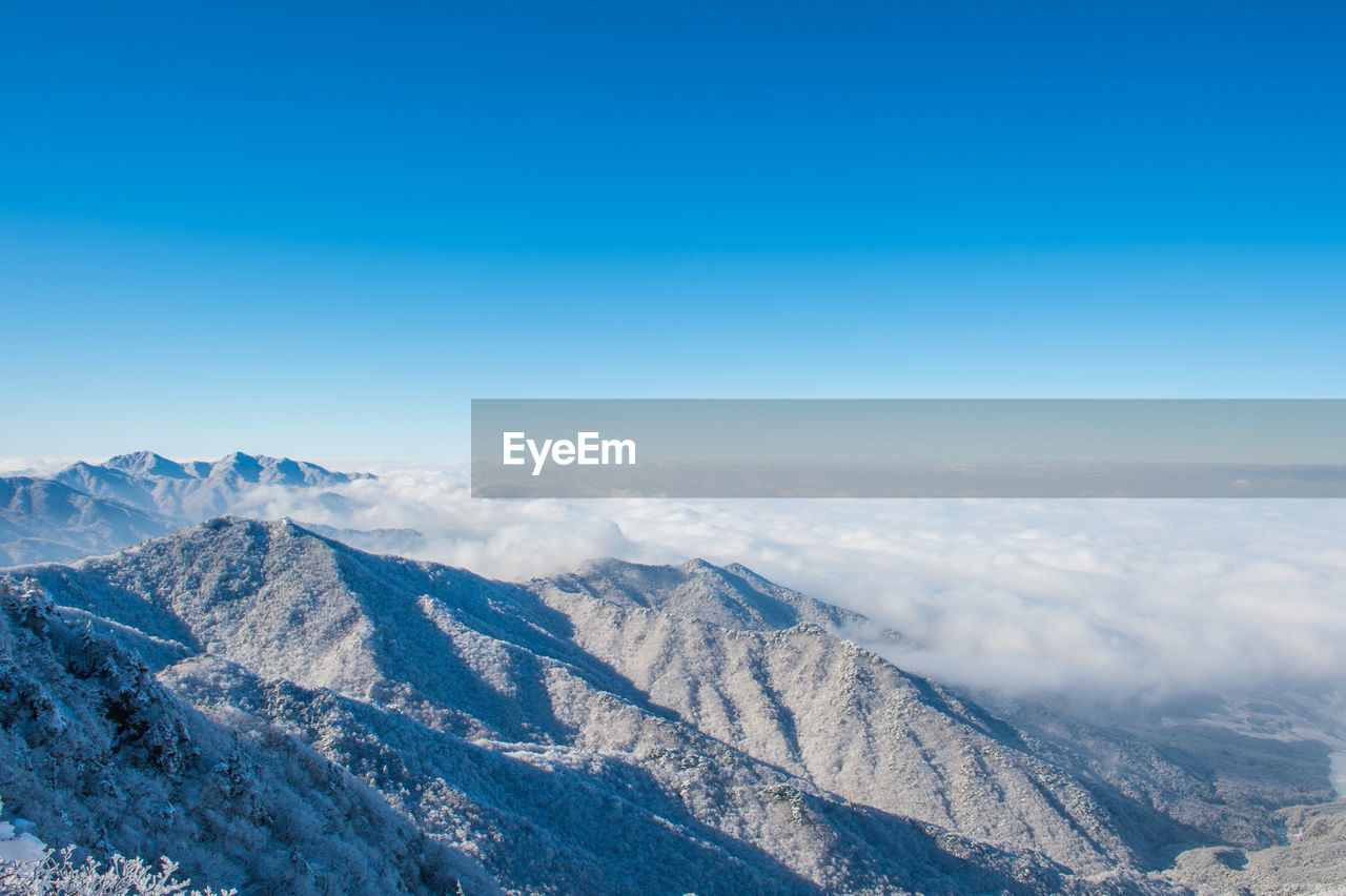 Scenic view of snowcapped mountains against blue sky