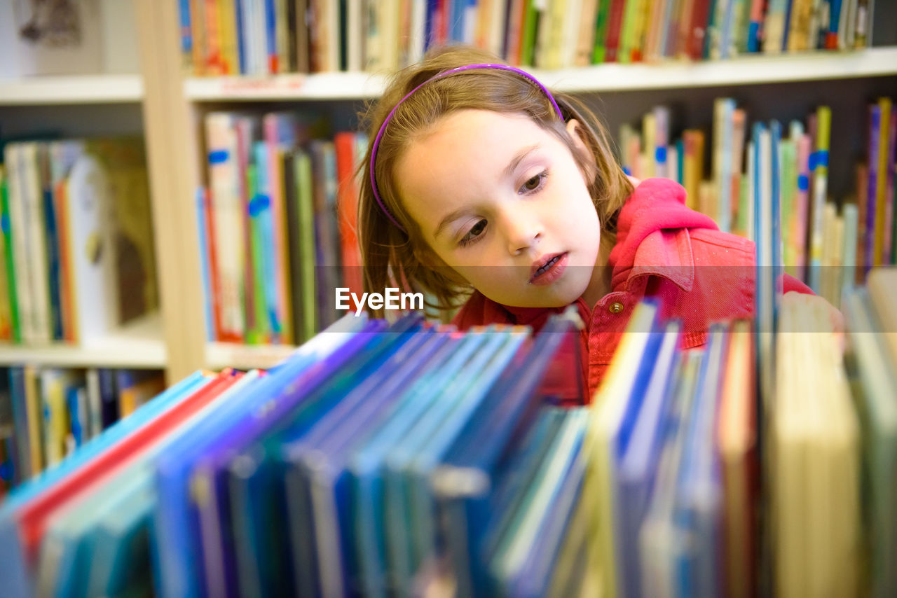 Girl selecting book while standing in library