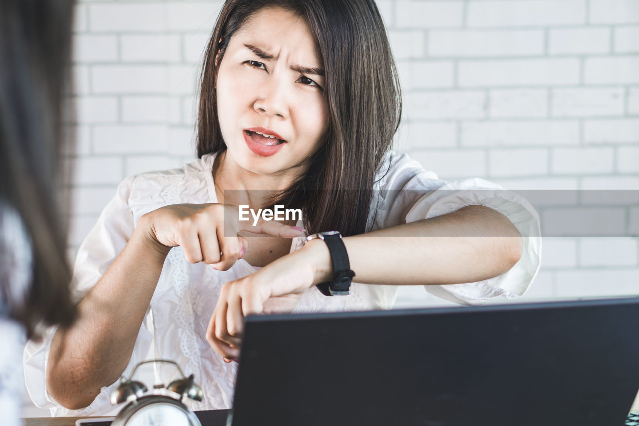 PORTRAIT OF A YOUNG WOMAN SITTING AT HOME