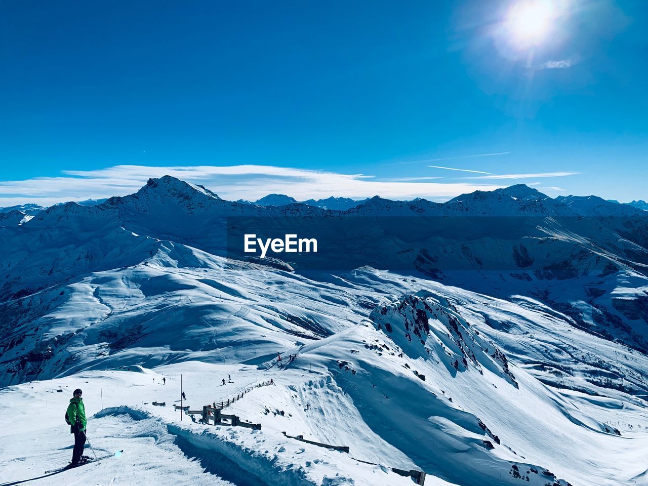 Man standing on snowcapped mountain against blue sky