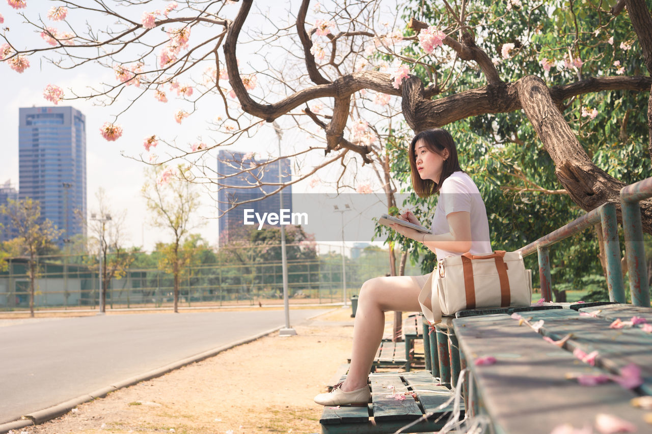 Woman sitting in park by city