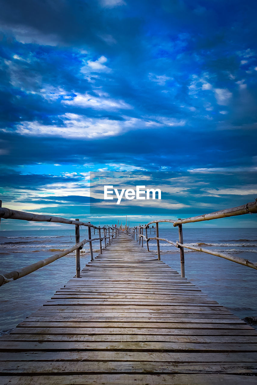 Wooden pier on sea against sky