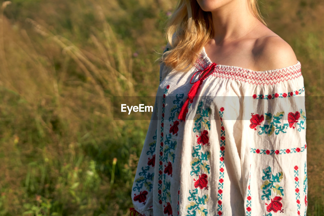 MIDSECTION OF WOMAN STANDING AT FIELD