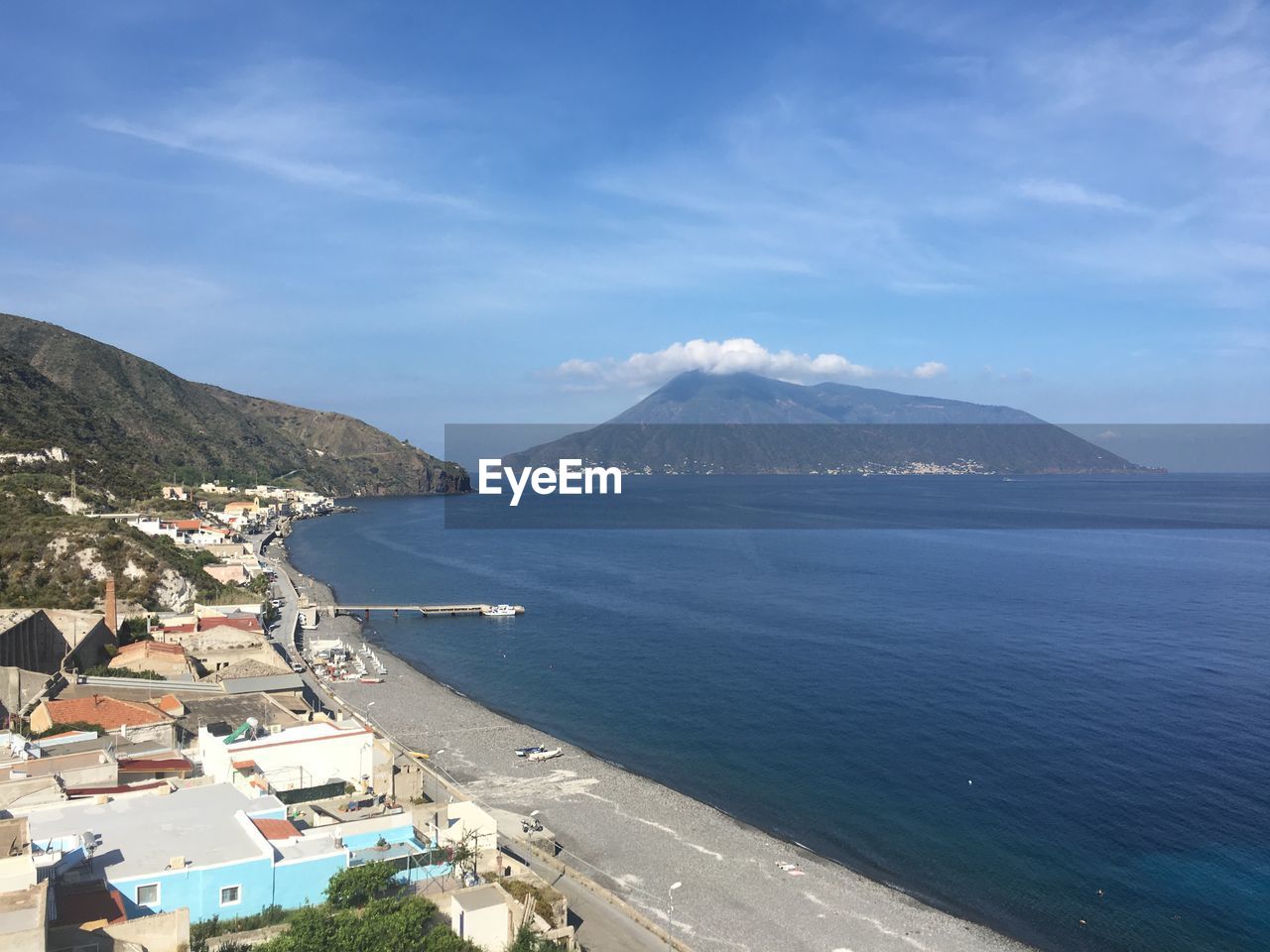 High angle view of sea and mountains against blue sky