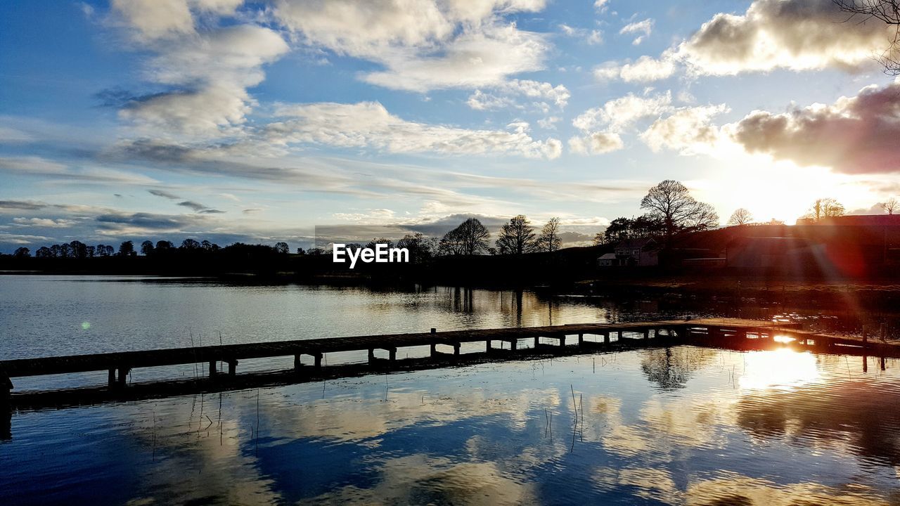 Scenic view of river against cloudy sky at sunset