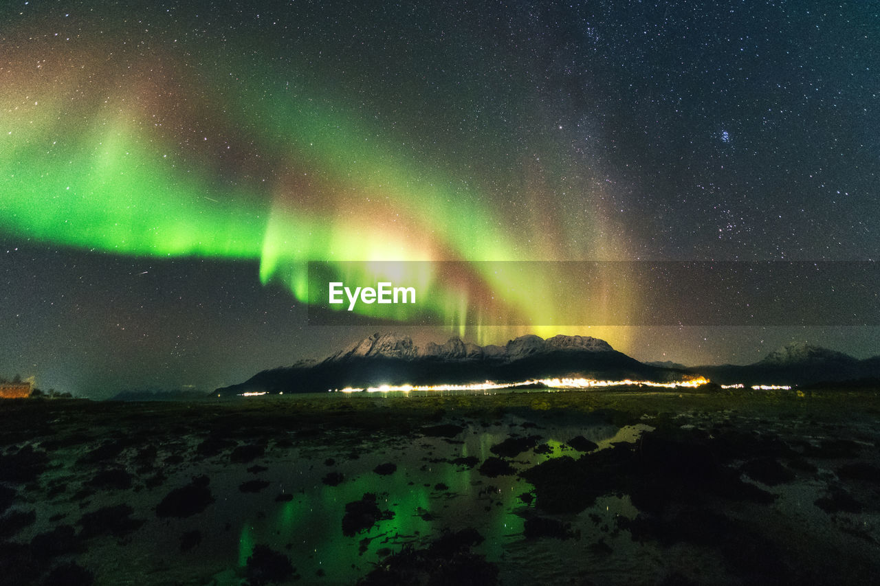 Northern lights over mountains at the rocky seashore