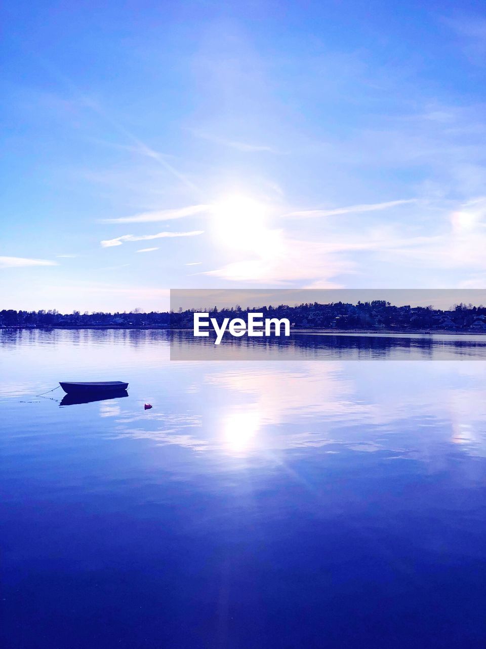 Boat on lake against sky during sunny day