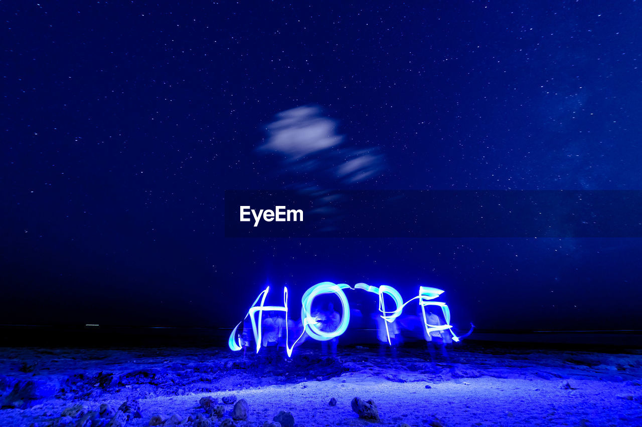 Illuminated hope text made by light painting at beach against star field