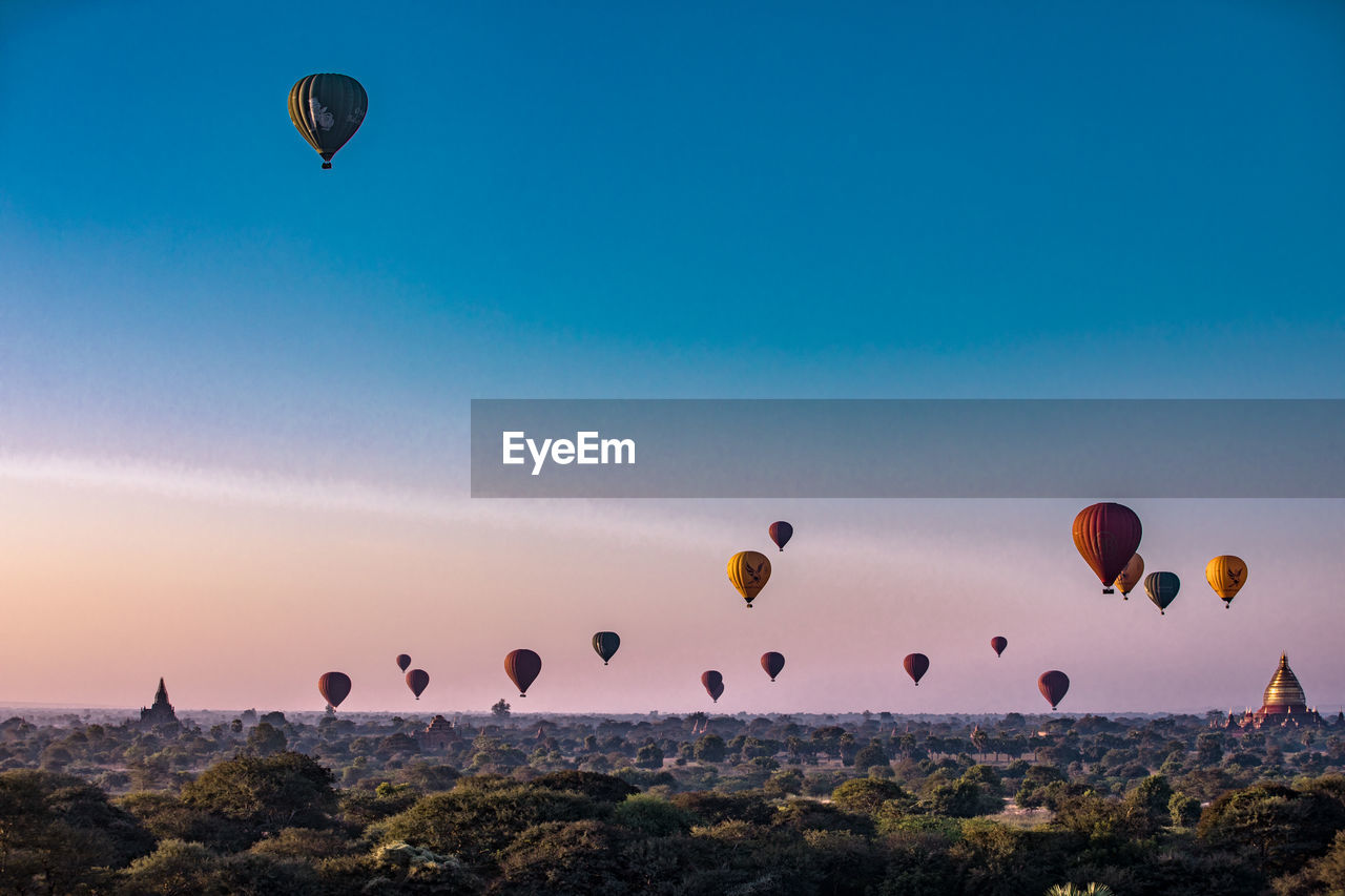 Hot air balloons flying over landscape in sky