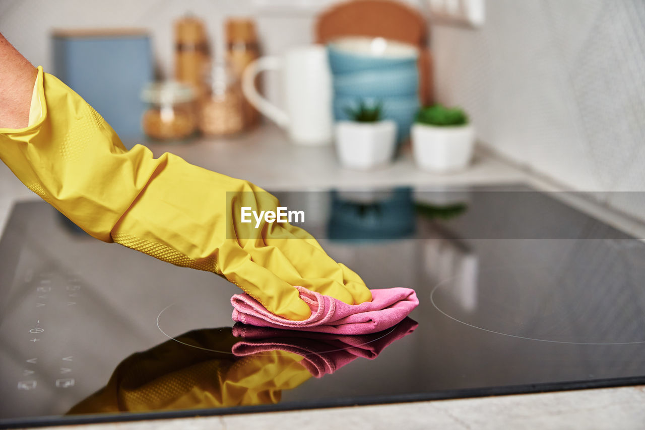 Woman in rubber gloves cleaning induction stove