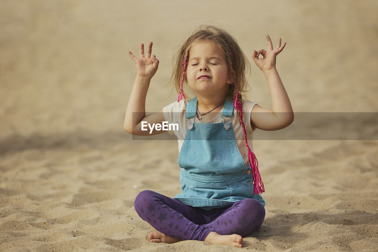 childhood, child, one person, sand, women, land, female, sitting, full length, nature, beach, happiness, front view, arm, smiling, limb, lifestyles, emotion, cute, portrait, enjoyment, innocence, arms raised, human limb, leisure activity, casual clothing, hairstyle, blond hair, clothing, fun, relaxation, person, spirituality, cheerful, meditating, yoga, exercising, outdoors, wellbeing, carefree, vitality, day, summer, sports