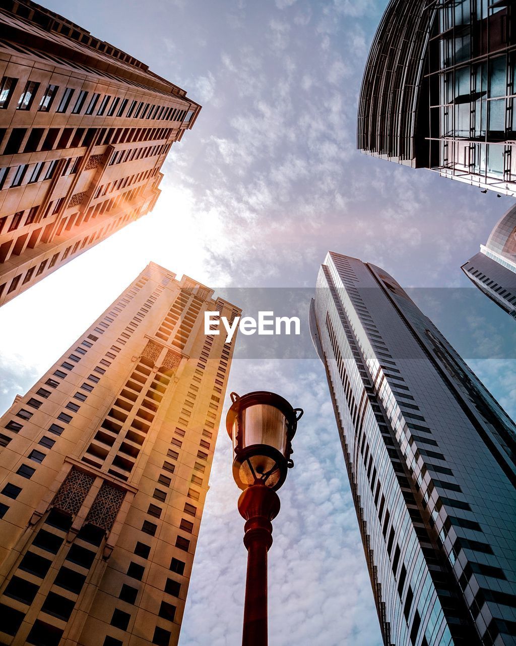 Low angle view of lamp post by buildings against sky