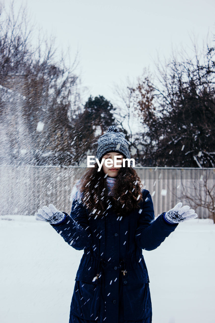 Photo in defocus. young attractive girl throwing snow with her arms. closeup shot.