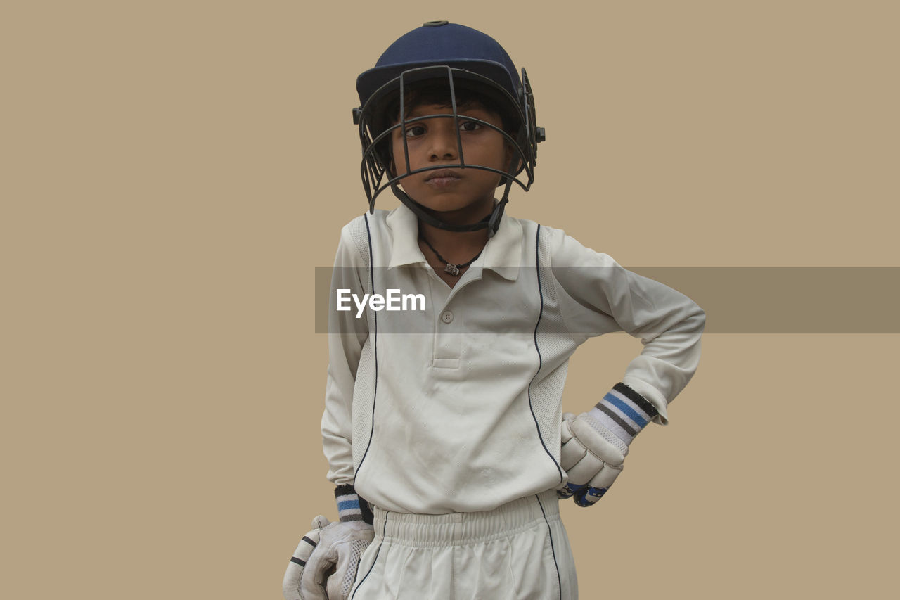 PORTRAIT OF BOY STANDING AGAINST ORANGE BACKGROUND