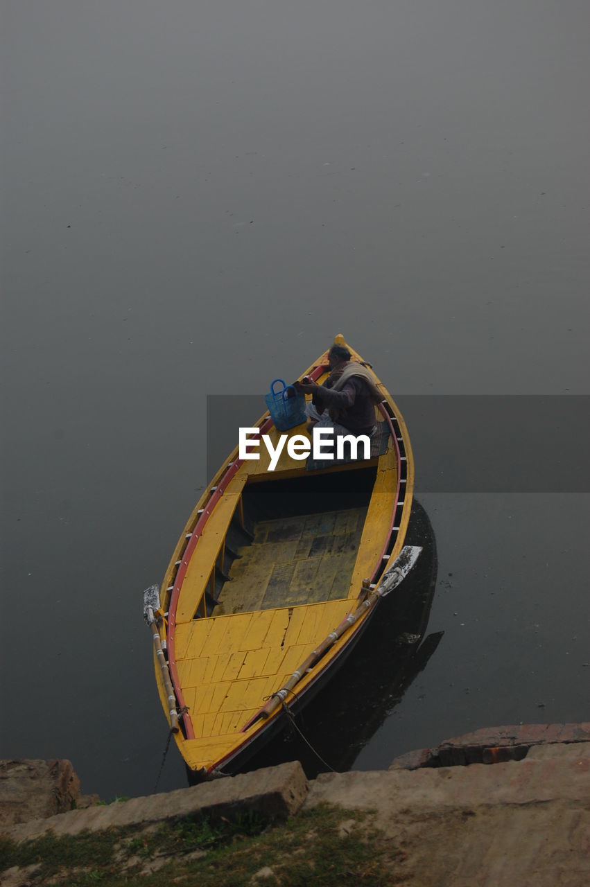 High angle view of man sitting on boat at lake