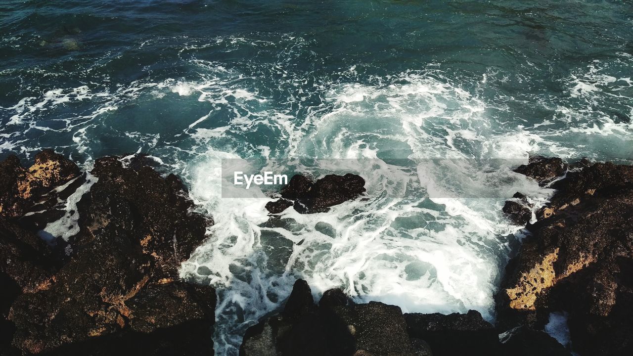 High angle view of wave splashing on rocks