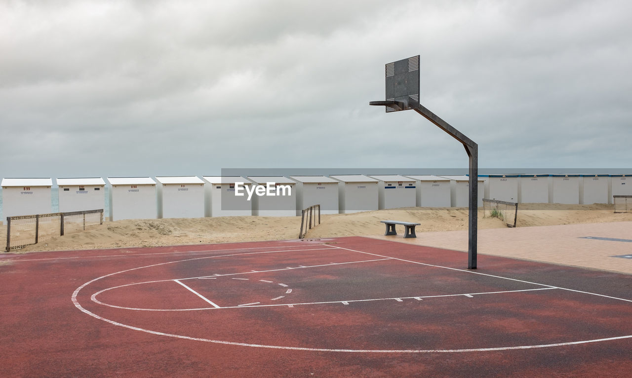 View of basketball hoop on beach against overcast sky