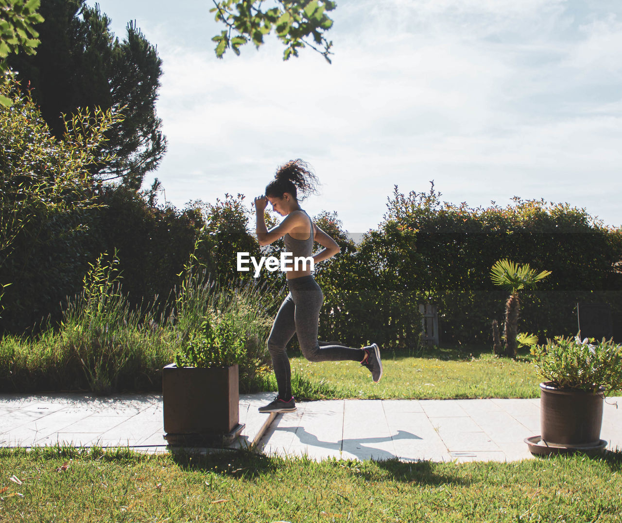 Young woman exercising in her home garden