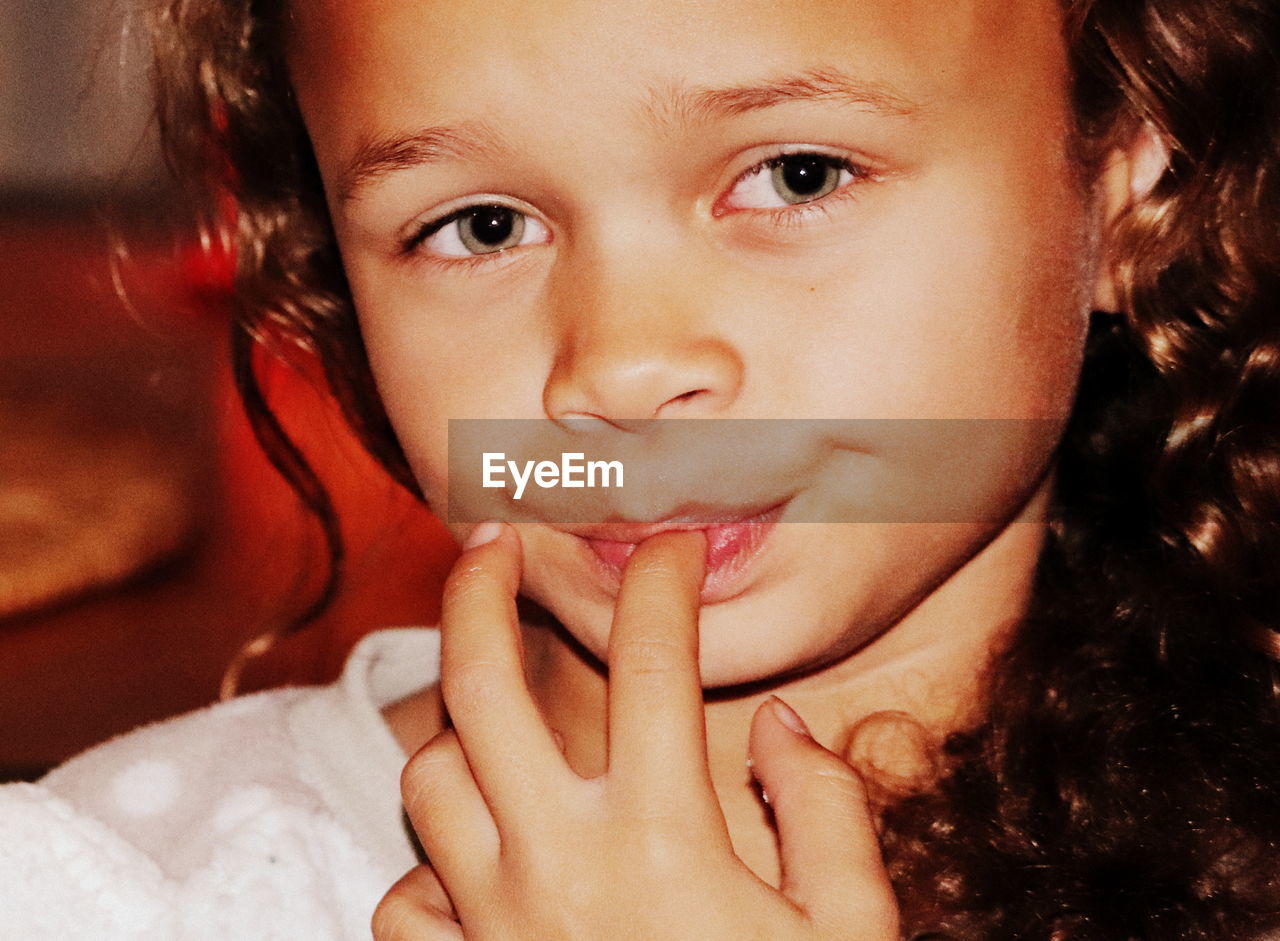 Close-up portrait of girl with finger in mouth