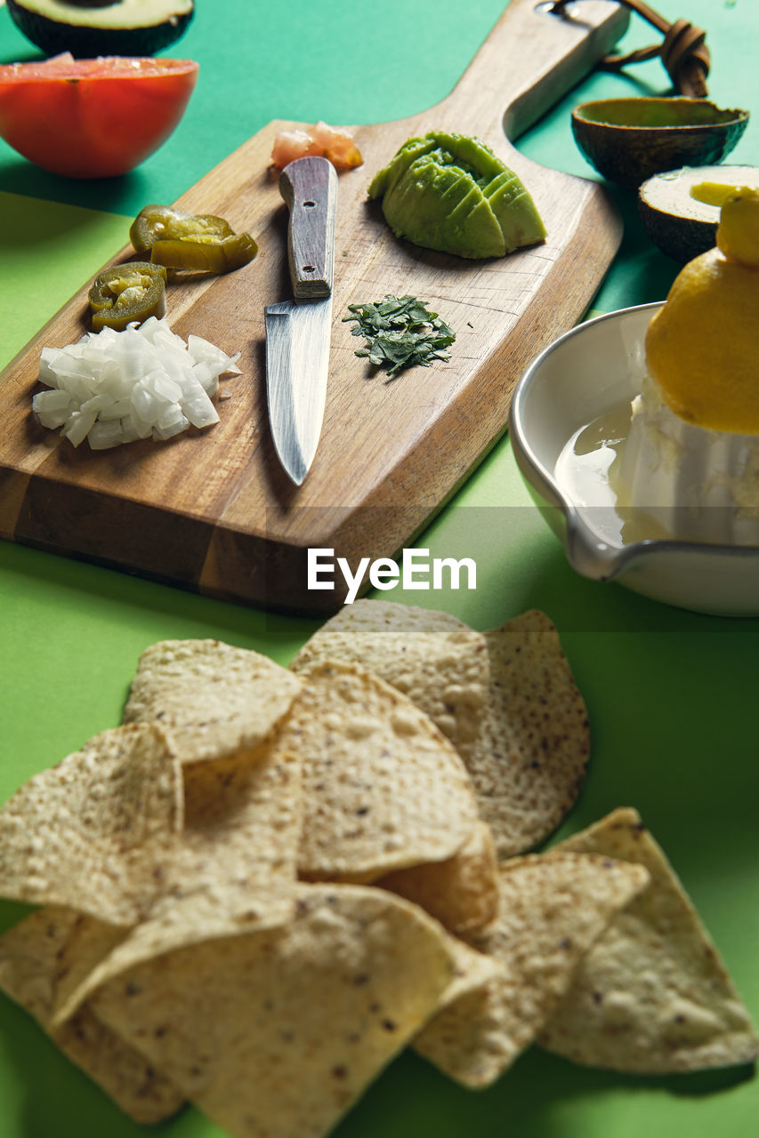 Ingredients on a green background to prepare a guacamole sauce