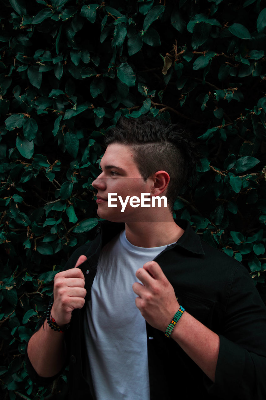 Young man looking away while standing outdoors