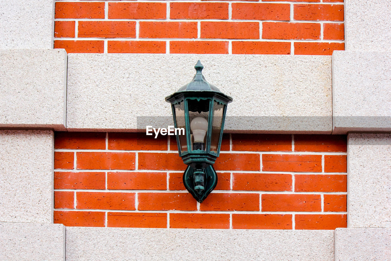 Close-up of street light against brick wall