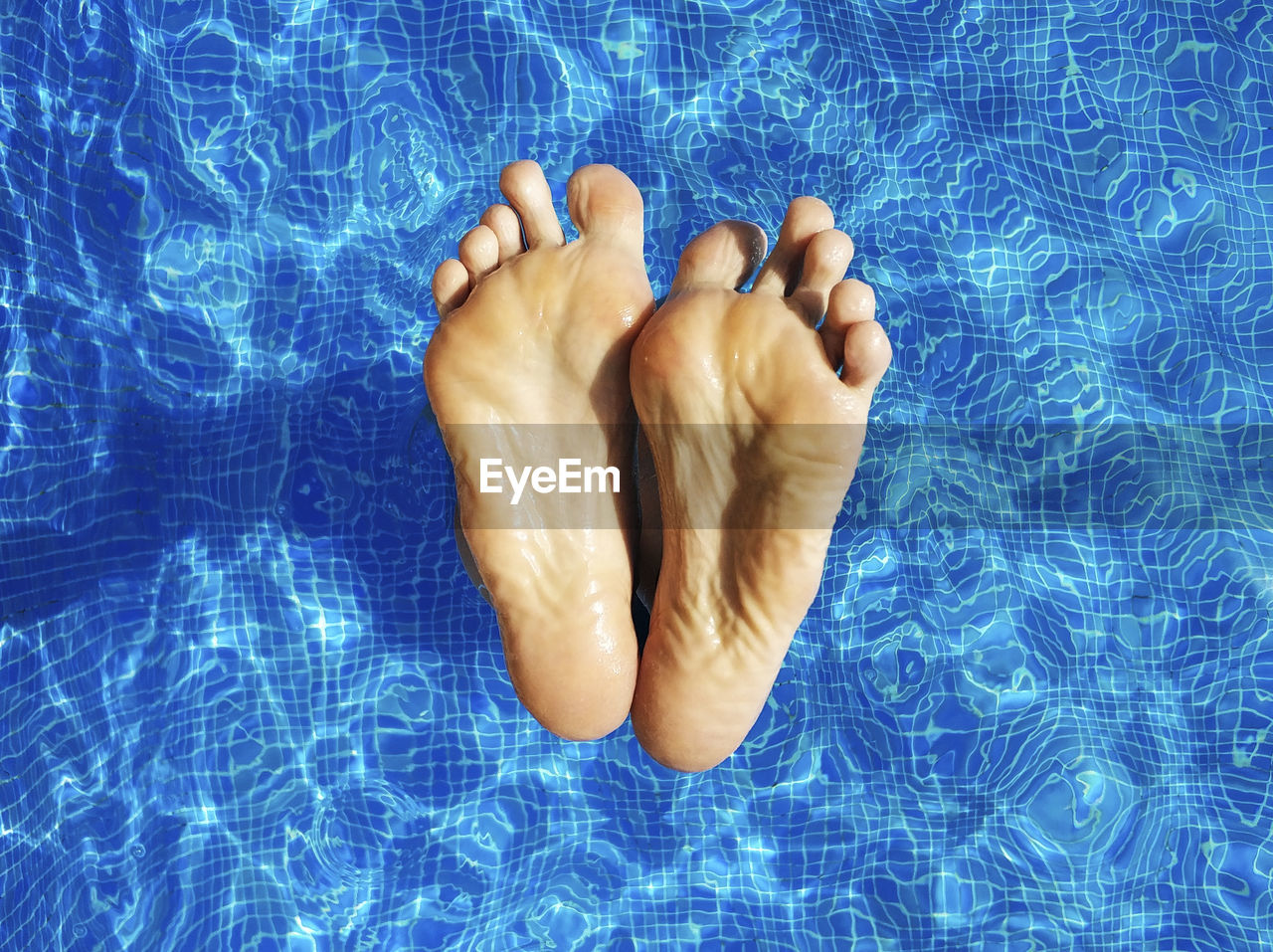 Low section of man with feet up in swimming pool