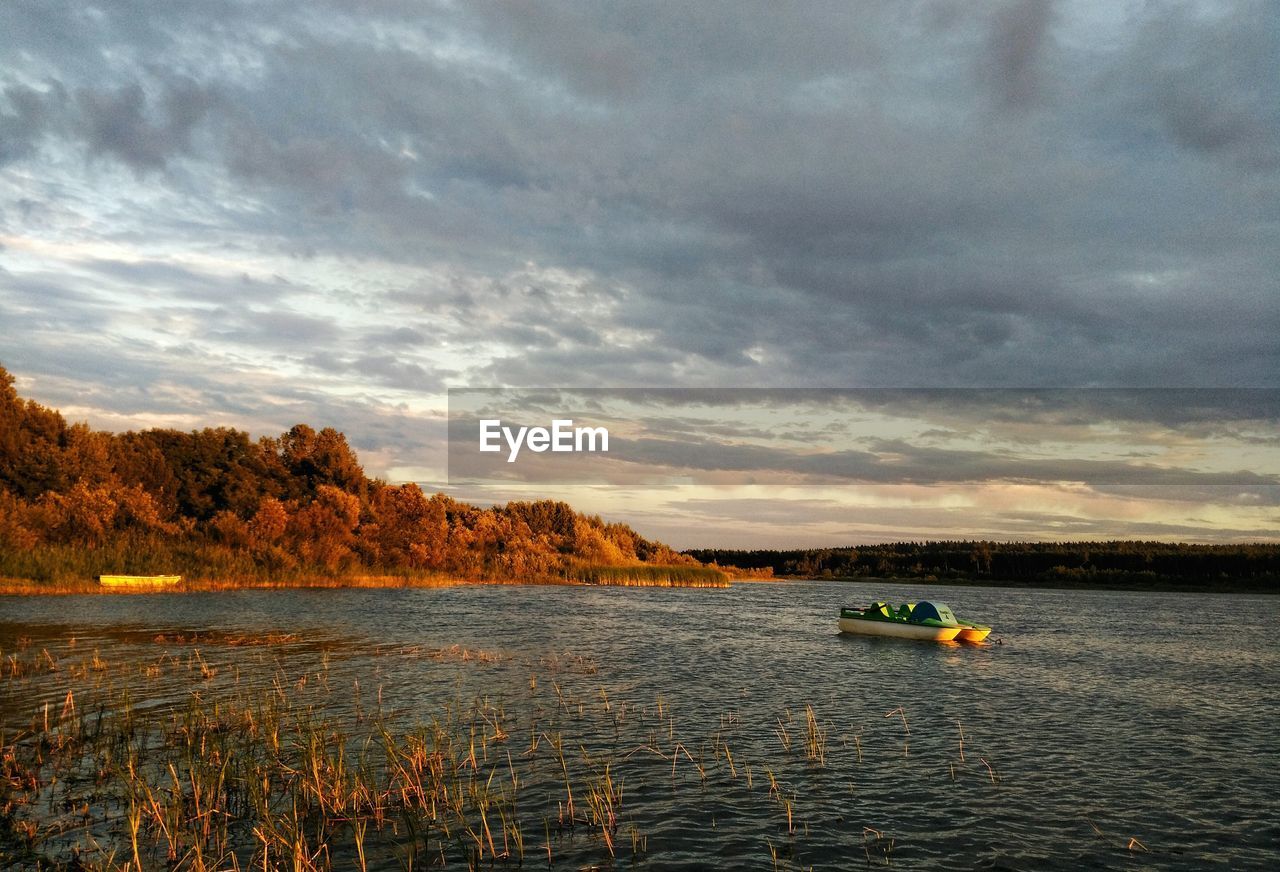 BOAT IN LAKE AGAINST SKY DURING SUNSET