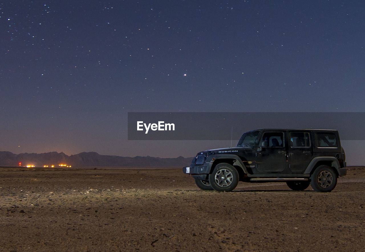 Off-road vehicle parked at desert against sky