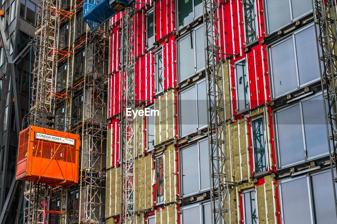 LOW ANGLE VIEW OF RED CONSTRUCTION SITE AGAINST BUILDINGS