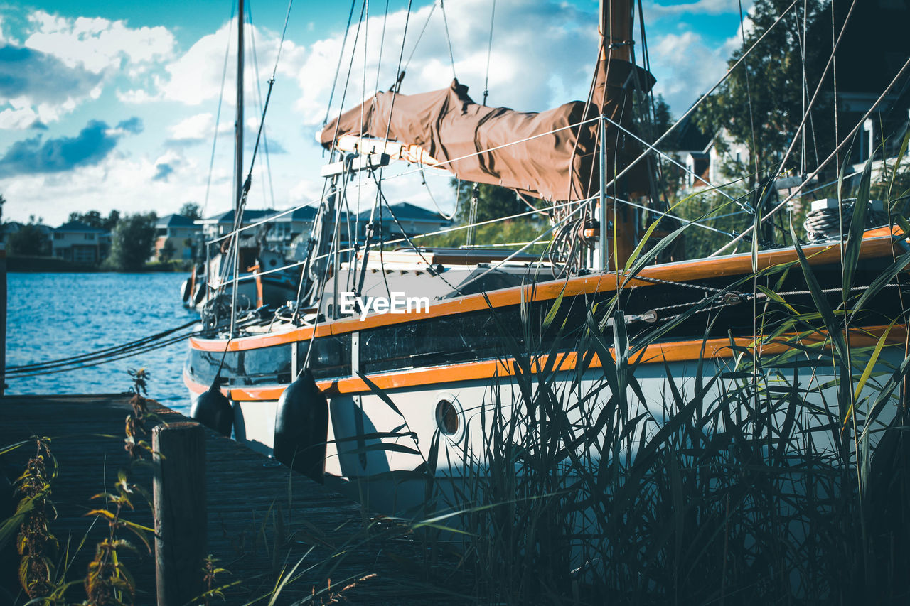 SAILBOATS MOORED IN SEA AGAINST SKY