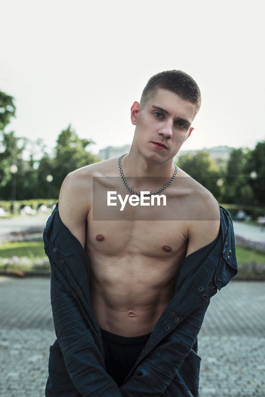 Portrait of young man with fully unbuttoned shirt at park